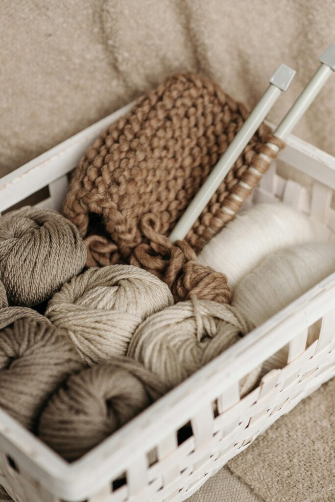 A rustic basket filled with wool yarn and knitting needles, ideal for crafts and hobbies.